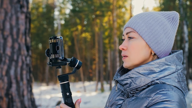 Videografo professionista che tiene una fotocamera DSLR su un dispositivo di stabilizzazione del giunto cardanico a 3 assi in inverno Operatore della fotografia al rallentatore