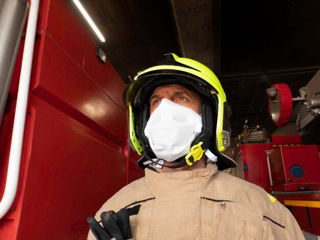 Vigile del fuoco dotato di equipaggiamento di intervento casco e mascherina per proteggersi dal covid 19