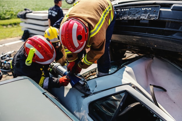 Vigili del fuoco che cercano di liberare l'uomo dall'auto incidentata. C'è un'auto si è schiantata in un incidente d'auto.