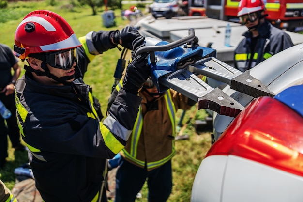 Vigili del fuoco in piedi vicino all'auto incidentata e cercando di capovolgerla.