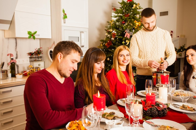 Vigilia di Natale. Cibo e bevande sul tavolo, candele accese. La famiglia insieme seleziona il Natale