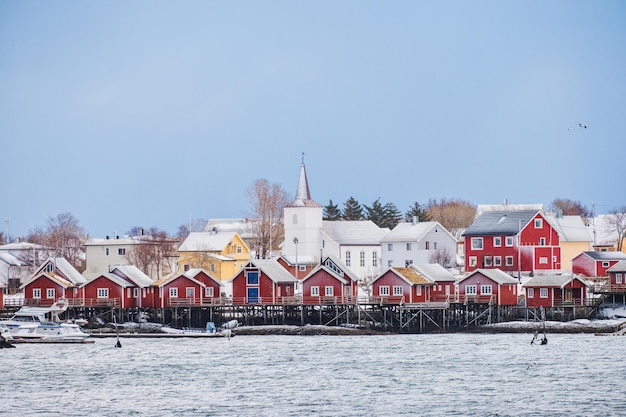 Villaggio di pescatori con chiesa cristiana nella città di reine sulla costa in una giornata di nevicata alle isole Lofoten in Norvegia