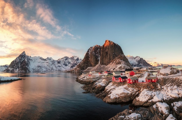 Villaggio di pescatori della casa rossa con la montagna della neve al tramonto