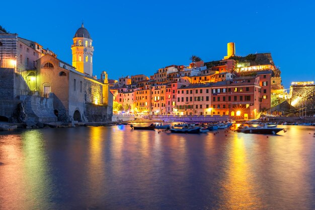 Villaggio di pescatori notturni Vernazza con la chiesa di Santa Margherita di Antiochia e la torre di avvistamento del Castello dei Doria, Cinque Terre, Parco Nazionale delle Cinque Terre, Liguria, Italia.