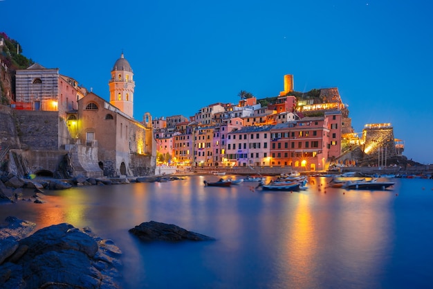 Villaggio di pescatori notturni Vernazza con la chiesa di Santa Margherita di Antiochia e la torre di avvistamento del Castello Doria, Cinque Terre, Parco Nazionale delle Cinque Terre, Liguria, Italia.