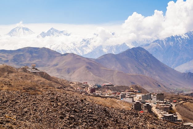 Villaggio tibetano in montagne dell'Himalaya con picco innevato