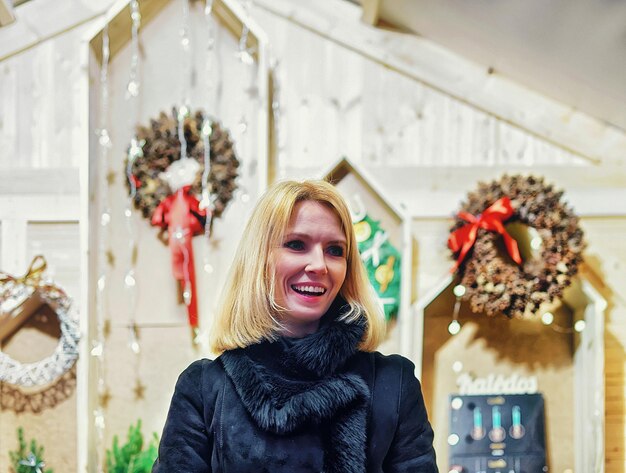 Vilnius, Lituania - 27 dicembre 2015: Donna sorridente che vende la corona di Natale sul mercatino di Natale a Vilnius. Messa a fuoco selettiva. Il filtro è applicato.