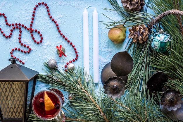 Vin brulè caldo con cardamomo arancia anice e cannella su sfondo blu Albero di Natale rami doni e coni