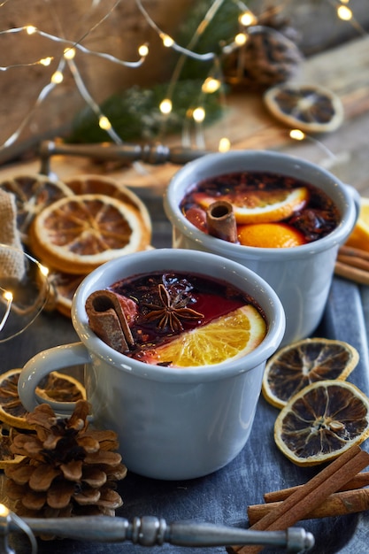 Vin brulé caldo di Natale in due tazze rustiche con frutta e spezie