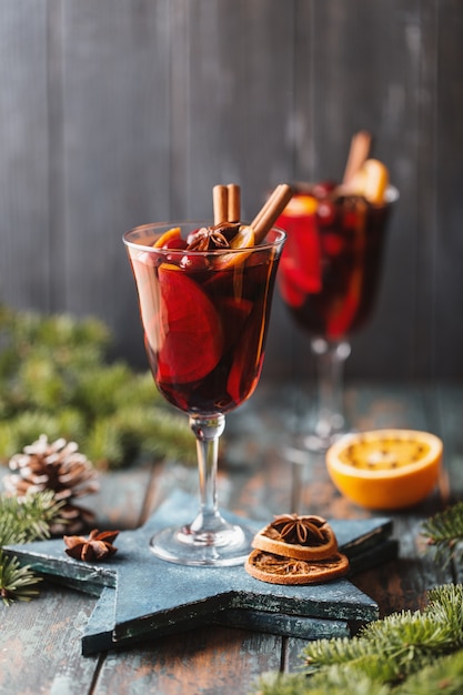 Vin brulè caldo di Natale in un bicchiere con spezie, agrumi e mirtillo rosso. Atmosfera natalizia.