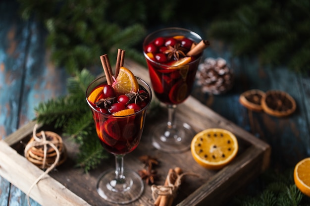 Vin brulè caldo di Natale in un bicchiere con spezie, agrumi e mirtillo rosso. Atmosfera natalizia.