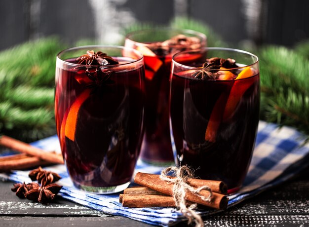 Vin brulè caldo di Natale in un bicchiere con spezie e agrumi. Vin brulè con cannella, anice e arancia.