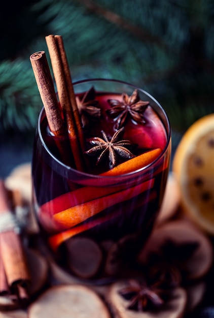 Vin brulè caldo di Natale in un bicchiere con spezie e agrumi. Vin brulè con cannella, anice e arancia.