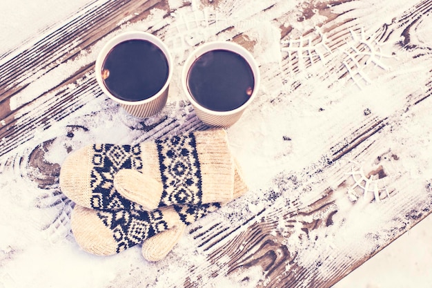 Vin brulè caldo e guanti lavorati a maglia sulla neve