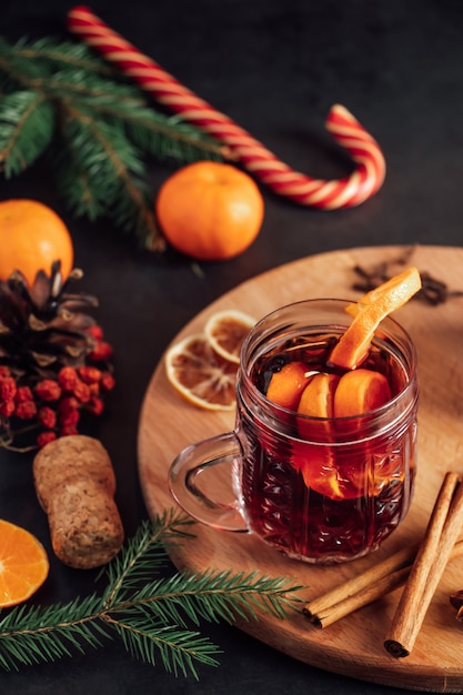 Vin brulé caldo in tazza di vetro su uno sfondo scuro. Bevanda calda di Natale con spezie e frutta.