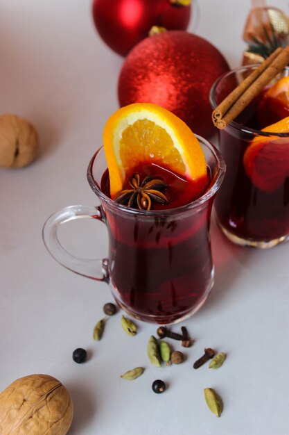 Vin brulè con fettine d'arancia, bastoncini di cannella con palline di Natale