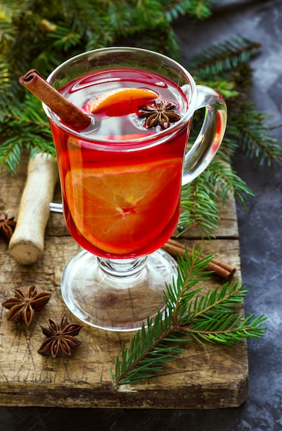 Vin brulè con spezie e albero di Natale su oscurità