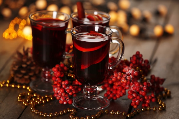 Vin brulé con spezie e albero di Natale su superficie in legno