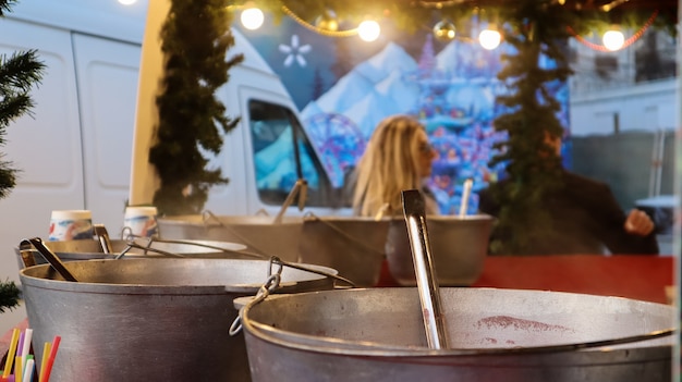 Vin brulé cotto sul fuoco all'esterno. Vitamine in una bevanda invernale. Ristorante di strada al mercatino di Natale in inverno. Vin brulé caldo. Vapore denso su calderoni di vino caldo.