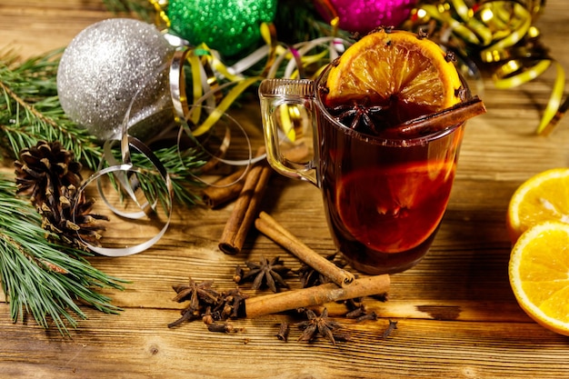 Vin brulé di Natale con spezie e decorazioni natalizie su tavola di legno