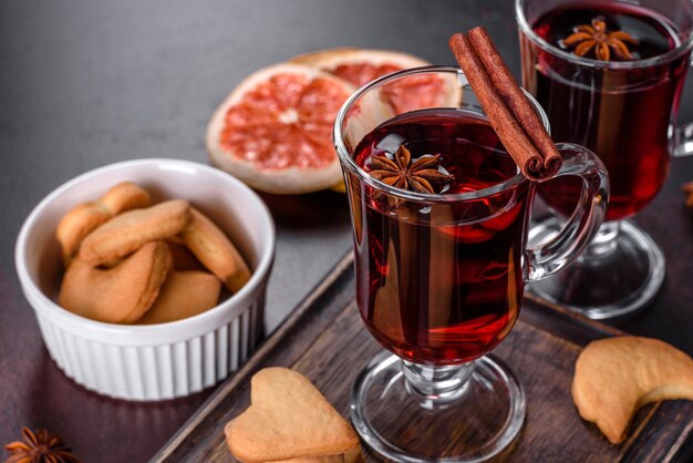 Vin brulé di Natale con spezie e frutta su un tavolo scuro.