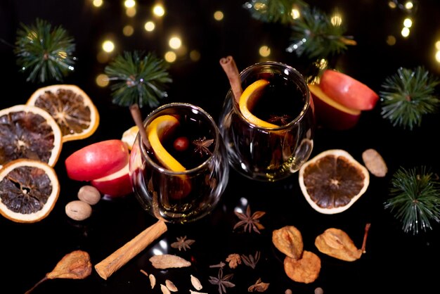 Vin brulé di Natale di vin rosso con spezie e frutta su sfondo nero. Bevanda calda tradizionale a Natale.