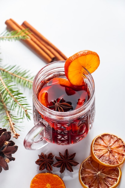 Vin brulé di riscaldamento di inverno in tazza di vetro su un fondo bianco.