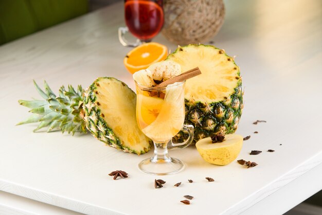 Vin brulè, grog e punch bevande alcoliche calde in tavola con decorazioni di stagione: ananas, cannella, mela, arancia, anice stellato. Bevanda speziata stagionale.