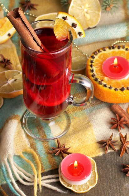 Vin brulé profumato in vetro con spezie e arance intorno sul tavolo di legno