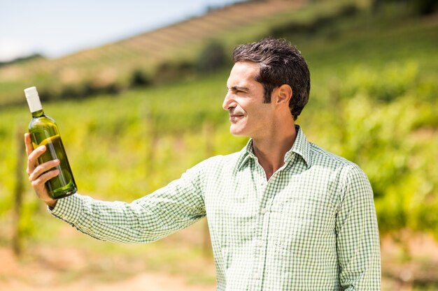 Vinaio sorridente che esamina bottiglia di vino