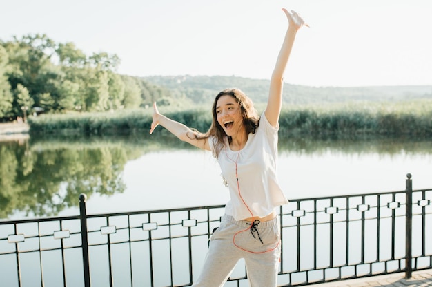 Vincitore come colpo orizzontale di stile di vita di giovane bella donna in abbigliamento sportivo che sorride mentre pa