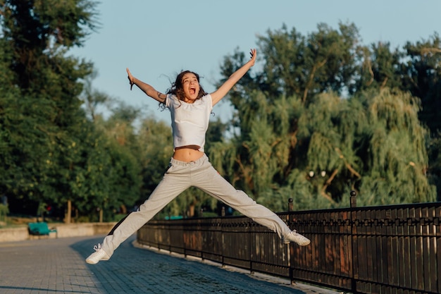 Vincitore come colpo orizzontale di stile di vita di giovane bella donna in abbigliamento sportivo che sorride mentre pa