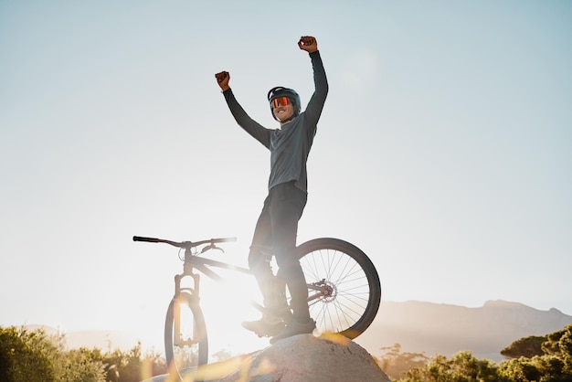 Vincitore di mountain bike o motociclista con successo sì o pompa a pugno per il raggiungimento dell'obiettivo di fitness o motivazione mockup all'aperto e cielo blu Sportivo che vince con la bicicletta d'avventura su una collina