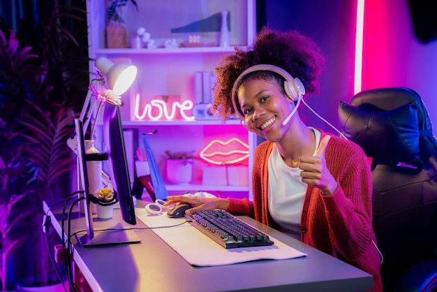 Vincitrice della squadra di streamer di gioco di una ragazza afroamericana che gioca a combattere online con Esport indossando le cuffie nella stanza con luci al neon Parlando con altri giocatori che pianificano strategie per vincere i concorrenti Tastemaker