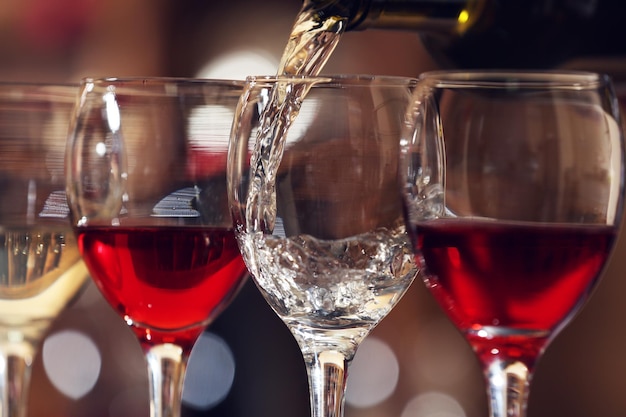 Vino bianco che versa nel primo piano di bicchiere di vino