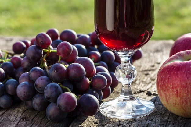 Vino in un bicchiere e uva su un tavolo di legno.