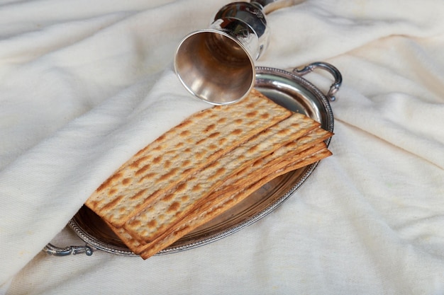 Vino kosher rosso con un piatto bianco di matzah o matza e una haggadah pasquale su un retro di legno d'epoca