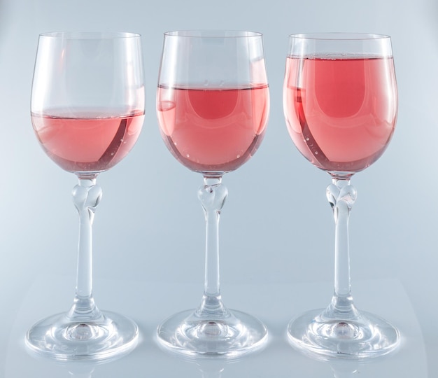 Vino rosato in bicchieri a stelo su sfondo bianco