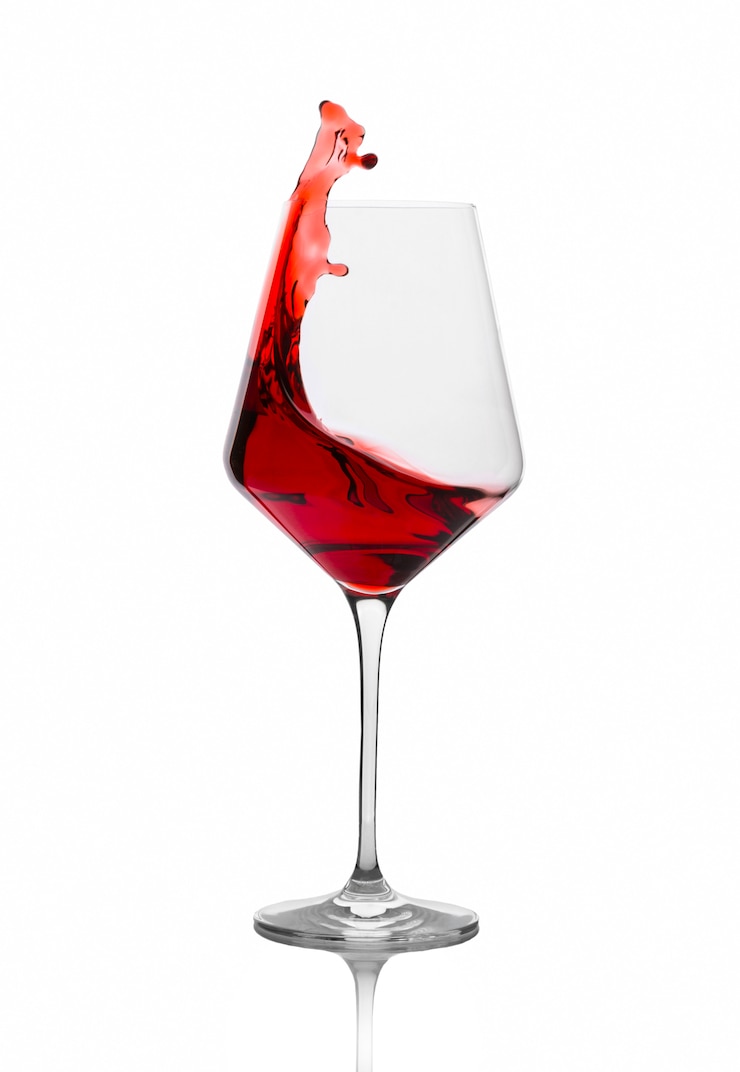 Foto vino rosso che spruzza da un vetro isolato sul bianco