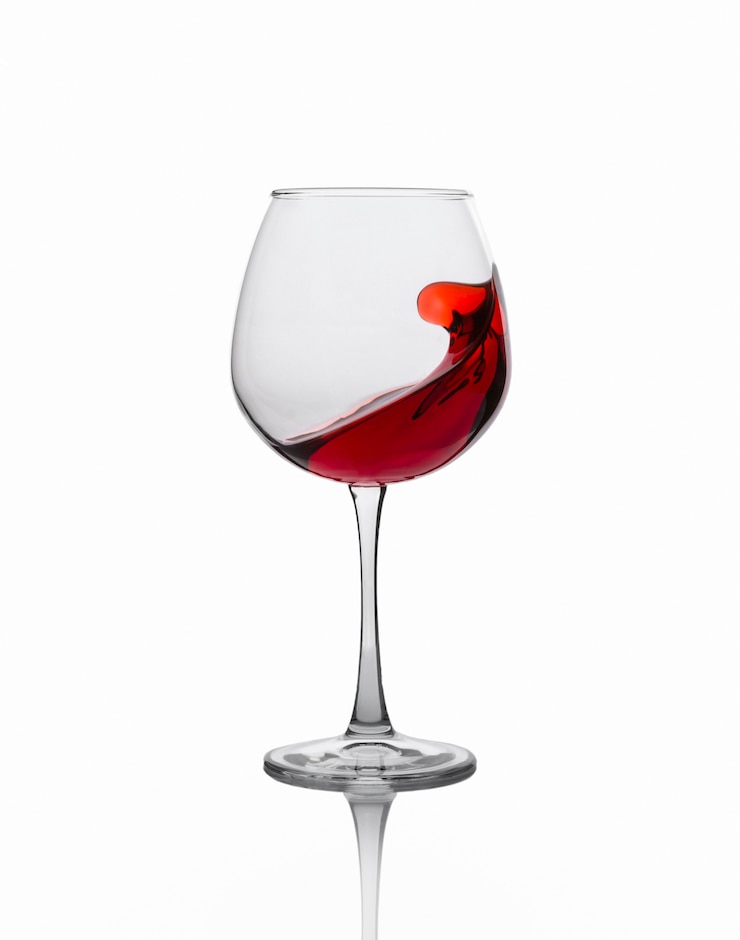 Foto vino rosso che spruzza da un vetro isolato sul bianco