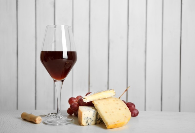 Vino rosso con formaggio e uva su fondo in legno