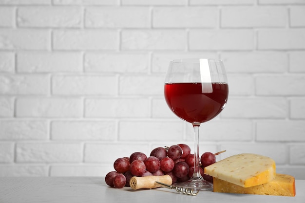 Vino rosso con uva e formaggio su sfondo muro di mattoni