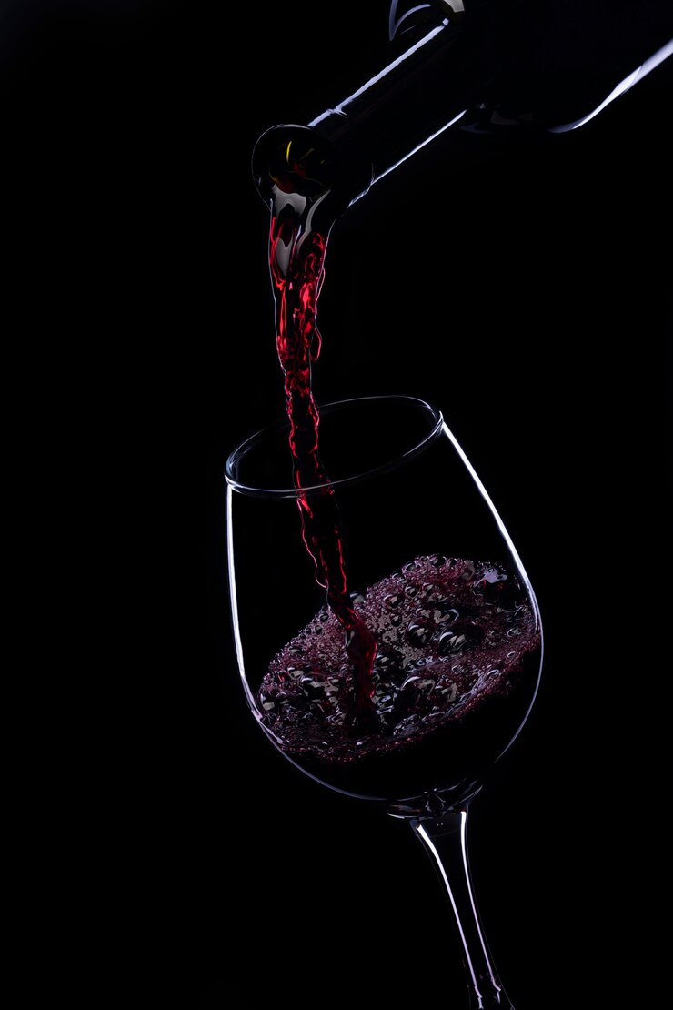 Vino rosso versato in un bicchiere da una bottiglia