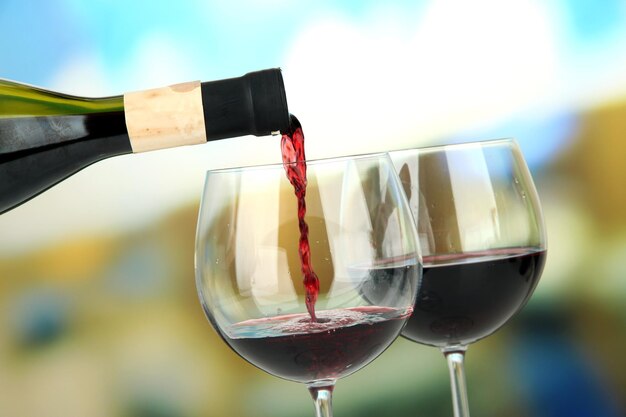 Vino rosso versato nel bicchiere di vino su sfondo luminoso