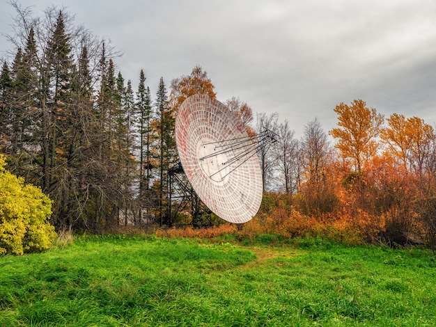 Vintage Radio Telescope, una grande parabola satellitare su uno sfondo di foresta di osservazione e cielo nuvoloso, radar in passato. Concetto di tecnologia, ricerca di vita extraterrestre, intercettazioni telefoniche dello spazio.