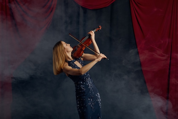 Violinista femminile con arco e violino, esibizione solista sul palco. Donna con strumento musicale a corde, arte musicale, musicista gioca sulla viola