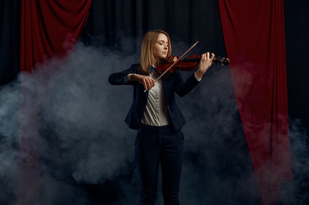 Violinista femminile con arco e violino, performance sul palco. Donna con strumento musicale a corde, arte musicale, musicista gioca sulla viola