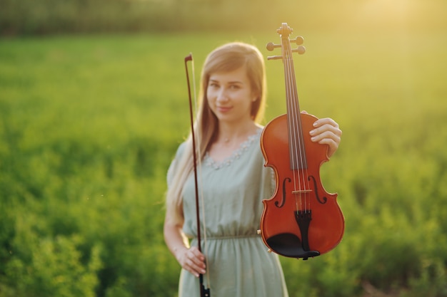 Violino nelle mani di un giovane violinista femminile nella luce del tramonto. donna, ragazza