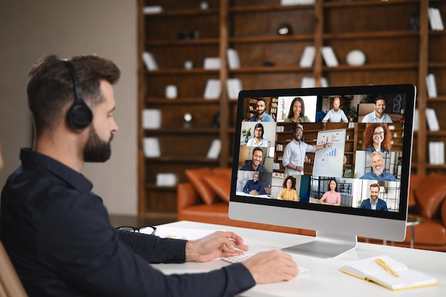 Virtual conference with employees Young man in formal clothes using pc for video call having video meeting with several people together Remote work