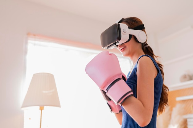 Virtual Metaverse Augmented Reality adulto femminile asiatico che lavora boxe in auricolare VR allenamento aerobico per pugilato pugno in realtà virtuale in soggiorno sfondo interno di casa